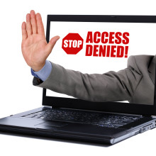 a man's hand extending from a laptop signally you to stop. 
